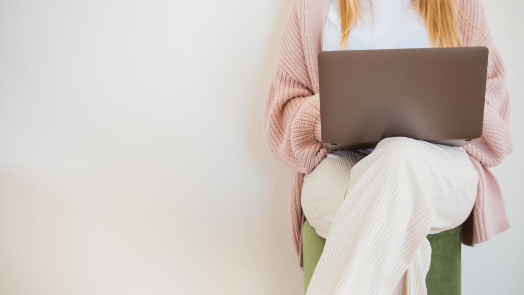 Una mujer está sentada leyendo contenidos desde su computador portátil. La redacción de contenidos institucionales